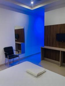 a blue room with a bed and a chair and a television at Hotel STAYVILLA in Guwahati