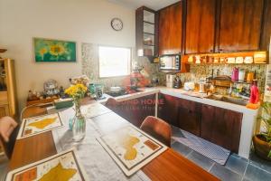 a kitchen with a counter and a table with flowers at Unique 2BR Gianyar Villa Rice Field View & Pool in Blahbatu