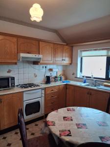 a kitchen with wooden cabinets and a table and a window at Teach Caitlin in Ballina