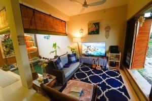 a living room with a couch and a tv at Unique 2BR Gianyar Villa Rice Field View & Pool in Blahbatu