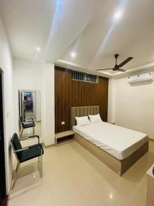 a bedroom with a bed and a fan and a chair at Hotel STAYVILLA in Guwahati
