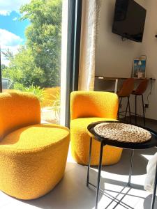 two orange chairs and a table in front of a window at Sous le figuier in Marseille