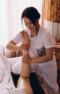 a woman sitting on a bed with a woman creating a dummy at Гимба in Podobovets