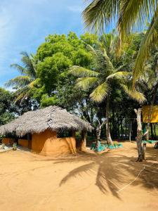 a small hut with a straw roof and palm trees at Eco Tree House Yala in Tissamaharama