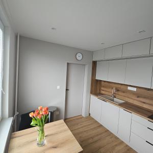 a kitchen with a vase of flowers on a wooden table at Apartmán Grand in Partizánske