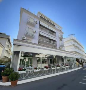 a white building with tables and chairs in front of it at Hotel Ornella in Bellaria-Igea Marina