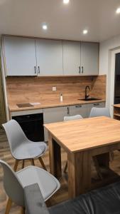 a kitchen with a wooden table and white chairs at Pod Wiatrakiem in Warta