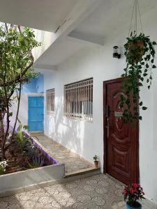 a wooden door in a white building with plants at velaris in Chefchaouen