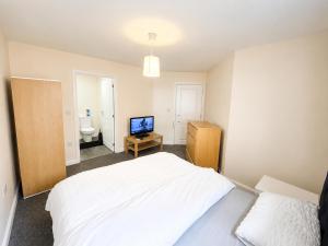 a bedroom with a white bed and a television at Private Ensuite room in Wolverhampton city centre in Wolverhampton
