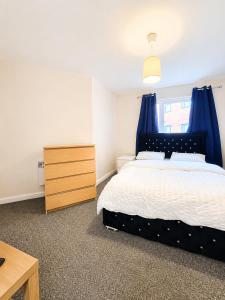 a bedroom with a bed with blue curtains and a dresser at Private Ensuite room in Wolverhampton city centre in Wolverhampton