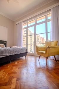 a bedroom with a bed and a chair and a large window at Maroca RIO in Rio de Janeiro
