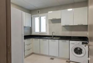 a white kitchen with a sink and a washing machine at The Pearl Nest Spacious 2BHK in Madinatna Better Than a Hotel, Halff the Price in Doha