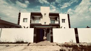 a white house with a fence in front of it at Appartements de rêve in Hennchir Ksar Rhaleb