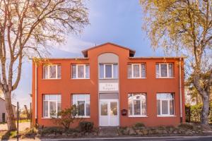 an orange house with trees in front of it at Muschelbank in Thiessow +5 photos