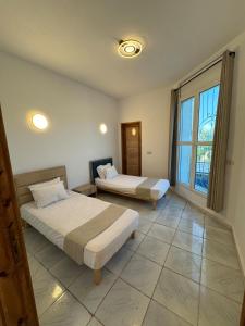 a bedroom with two beds and a large window at Villa Pieds dans l eau entre Lagune et Montagne in Ghār al Milḩ