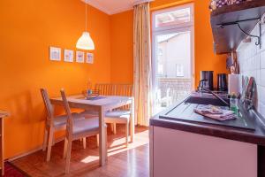 a kitchen with orange walls and a table with chairs at Wellengang in Thiessow