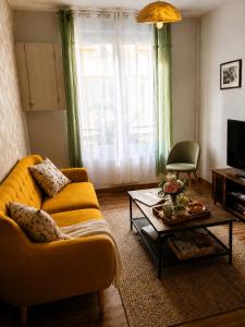 a living room with a yellow couch and a coffee table at Gîte cosy Vertus avec terrasse privé proche maisons de Champagne Epernay Reims in Vertus