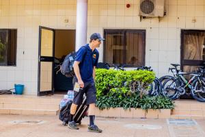 a man with a backpack standing in front of a building at Atlantic Beach Hôtel Bénin in Cotonou
