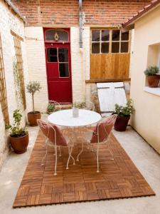 a table and chairs on a patio with a red door at Gîte cosy Vertus avec terrasse privé proche maisons de Champagne Epernay Reims in Vertus
