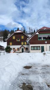 a large house with snow in front of it at Rosso Betulle, Free Park and Ski room in Camporosso in Valcanale