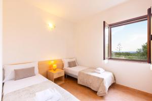 a bedroom with two beds and a window at Molara Ichnos House in San Teodoro
