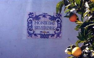 a sign on a wall next to an orange tree at Monte das Silveirinhas - Casa Rural in Silveiras