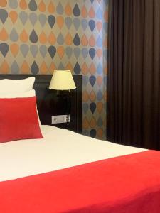 a bedroom with a bed with a red pillow and a lamp at East Gate Boutique Hotel in Tbilisi City