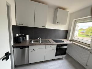 a kitchen with white cabinets and a sink and a window at Sofia2 in Urschmitt