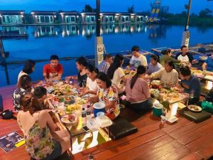 a group of people sitting at tables eating food at มีดี ฟาร์ม โฮมสเตย์ in Ban Klam +6 photos