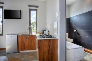 a kitchen with a stove and a sink and a tub at Le Morne Base - Stylish, Pool & Rooftop in La Gaulette
