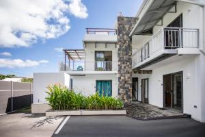 a white house with a balcony and plants at Le Morne Base - Stylish, Pool & Rooftop in La Gaulette