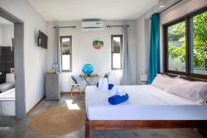 a bedroom with a large white bed and windows at Le Morne Base - Stylish, Pool & Rooftop in La Gaulette