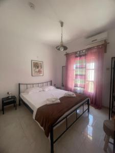 a bedroom with a bed and a window with pink curtains at Ariana's apartment in Orfánion