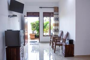 a living room with a television and a table and chairs at minidu resort in Ambalantota