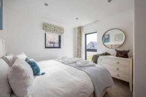 a white bedroom with a bed and a mirror at Jurassic in Dorchester
