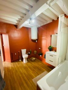 a bathroom with orange walls and a toilet and a sink at Appartement hyper centre in Caen