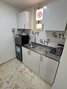 a kitchen with white cabinets and a sink and a refrigerator at روز للاستديوهات المفروشة in Abu Dhabi
