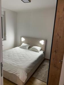 a bedroom with a bed with white sheets and pillows at Apartman 15 in Novi Sad