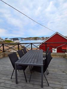 a picnic table and chairs on a deck with a red barn at Fiskehuset Havnes in Averoy