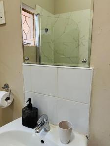 a bathroom with a sink and a mirror on the wall at Brilliant Home in Gaborone +14 photos