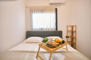 a bed with a tray of fruit on a table at Iraklia Coral in Nea Irakleia