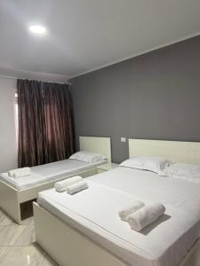 two beds in a room with white sheets and towels at Hotel del Mar in Shëngjin