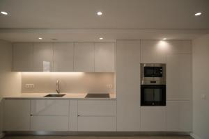 a white kitchen with a sink and a microwave at Alba Esposende - Balcony Apartment in Esposende