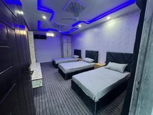 two beds in a room with purple lights at Ajk bed & Breakfast in Gura Gujarān
