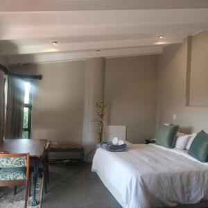 a bedroom with a bed and a table and a desk at the Moonflower in Mbabane