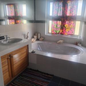a bathroom with a tub and a sink and a window at the Moonflower in Mbabane