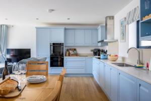 a kitchen with blue cabinets and a wooden table at Dawn Lighthouse in Dorchester +32 photos