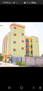a large yellow building with colorful windows next to a fence at Résidence Hôtel KOUNAF GROUP in Parakou