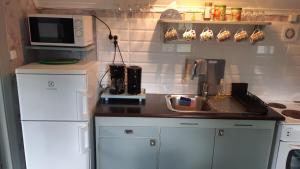 a small kitchen with white cabinets and a microwave at Lunden in Vittaryd