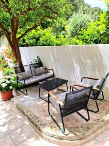 three chairs and a table and a bench on a patio at Bugenvilija in Duće